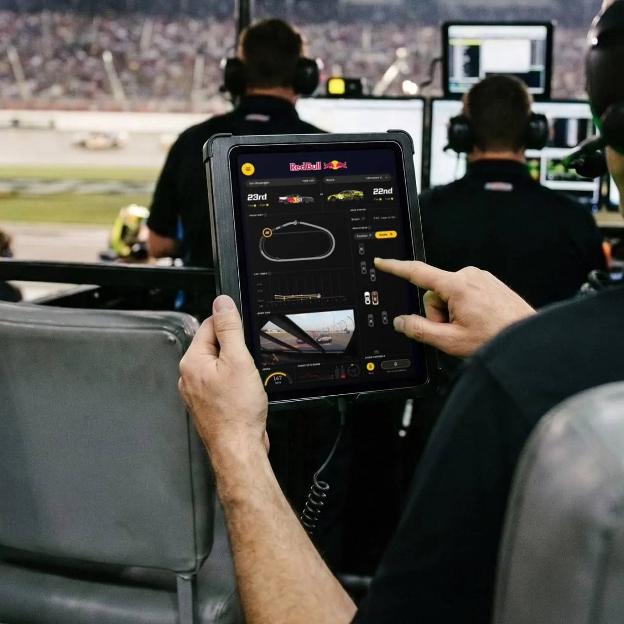 A VIP guest in the Trackhouse pit box holds the team iPad app and taps through live race telemetry